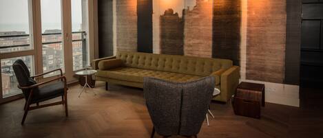 Una sala de estar moderna con un ventanal grande, un sofá, un sillón y una mesita.