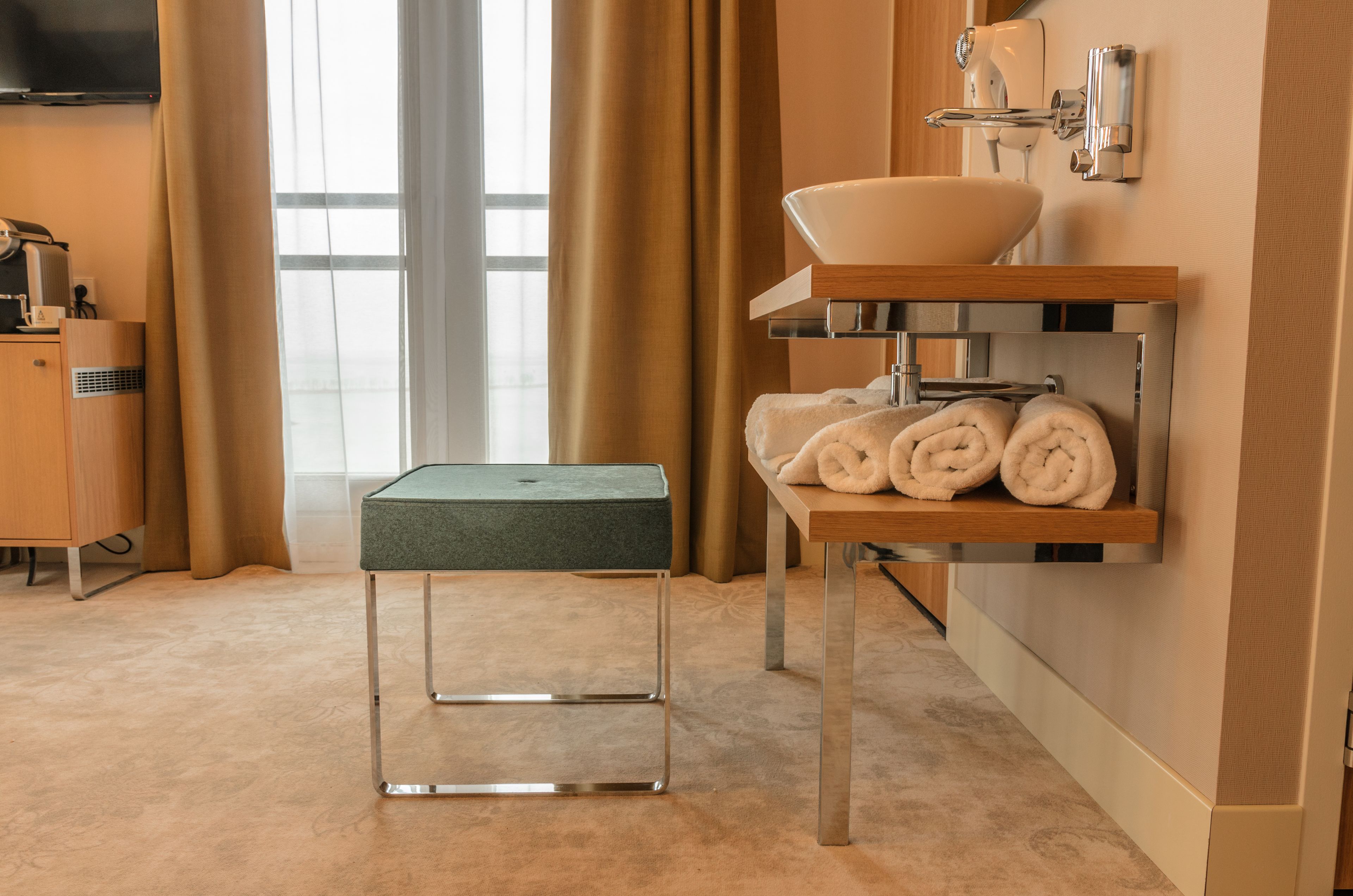 A modern bathroom with a sink, towel rack, and a small table.