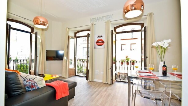 Un salon moderne avec un canapé, une table à manger et des chaises, ainsi que de grandes fenêtres.