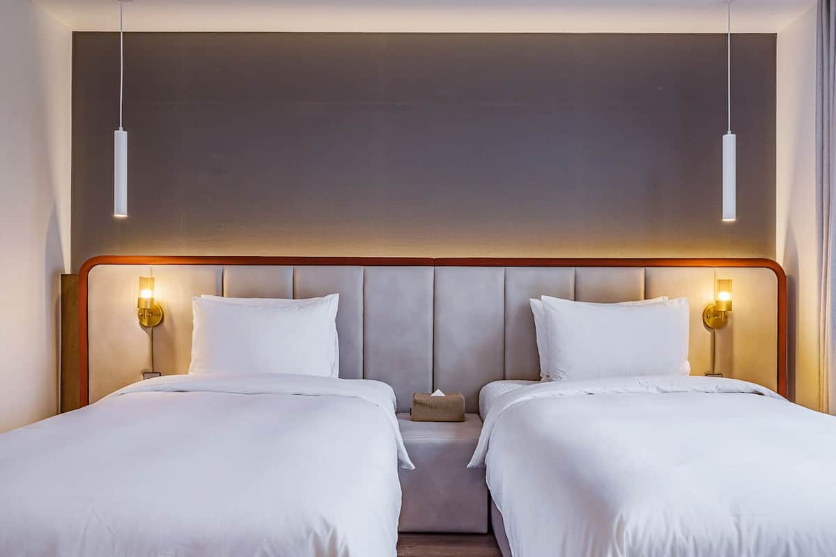 A double room with two beds, a wooden headboard, and bedside lamps.