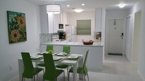 A modern kitchen with white cabinets, a central island, and green chairs.