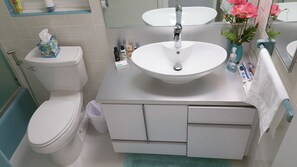 A bathroom with a white toilet, a white sink, and a mirror above the sink. There is a blue towel hanging on the wall and a trash can next to the toilet. - Downtown Hollywood Boutique Hotel (Hollywood)