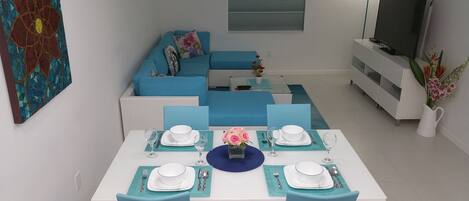 A dining area with a white table set for two, blue chairs, and a blue placemat.