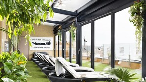 Eine Dachterrasse mit Liegestühlen, künstlichem Rasen und hängenden Pflanzen.