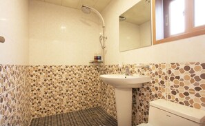Un baño con ducha, lavamanos e inodoro. Las paredes tienen un diseño de mosaicos.