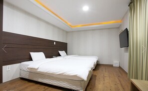 Un dormitorio con una cama grande, cabecera de madera, televisor de pantalla plana y piso de madera.
