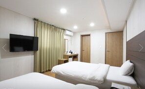 Habitación de hotel con dos camas, televisión, escritorio y baño.