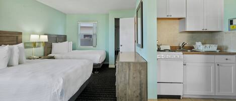 A hotel room with two beds, a kitchenette, and a bathroom.