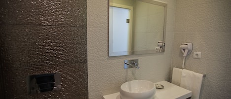 A bathroom with a textured wall, a white sink, a mirror, and a hairdryer.