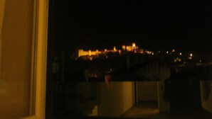 Vista nocturna de un paisaje urbano con edificios iluminados, vista a través de una ventana.