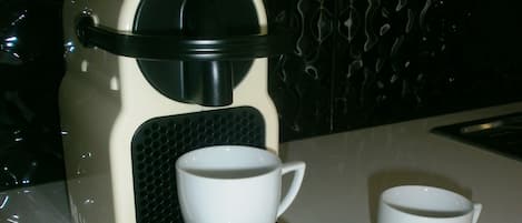 Une machine à café avec deux tasses et une cuillère sur une table.