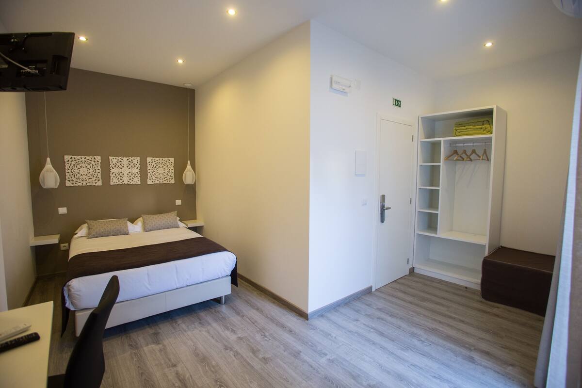 A modern hotel room with a bed, bedside table, and a walk-in closet.