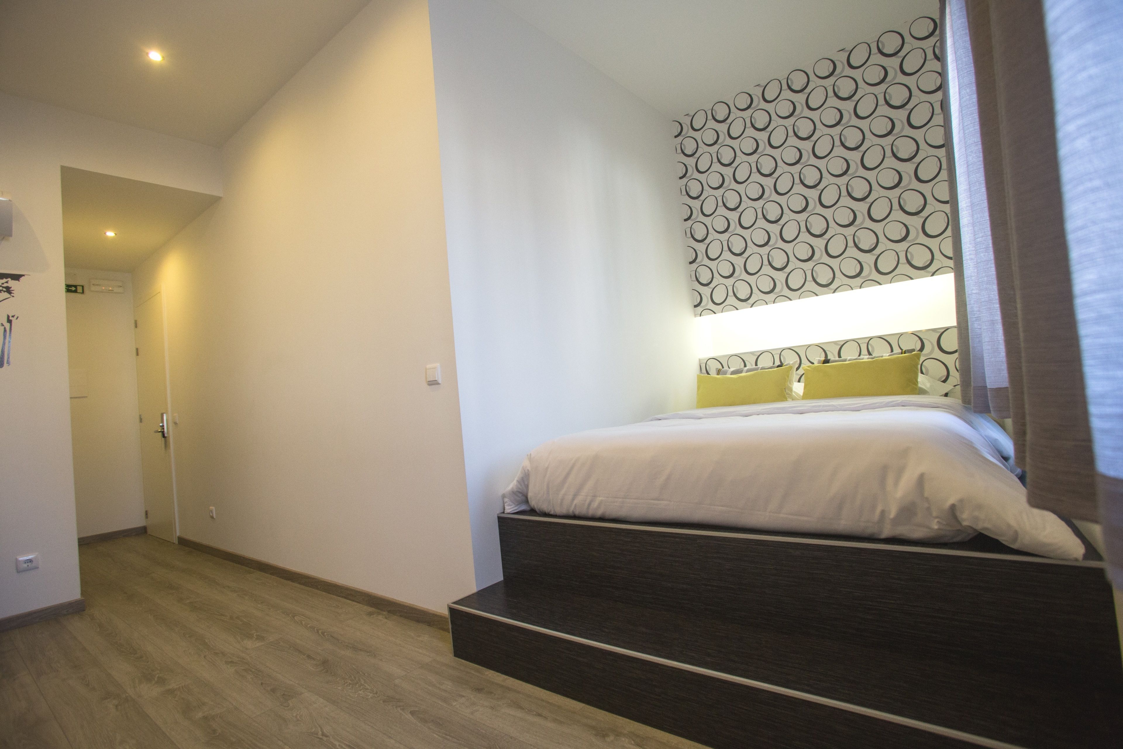 Un dormitorio con cama, cabecera estampada y suelo de madera.