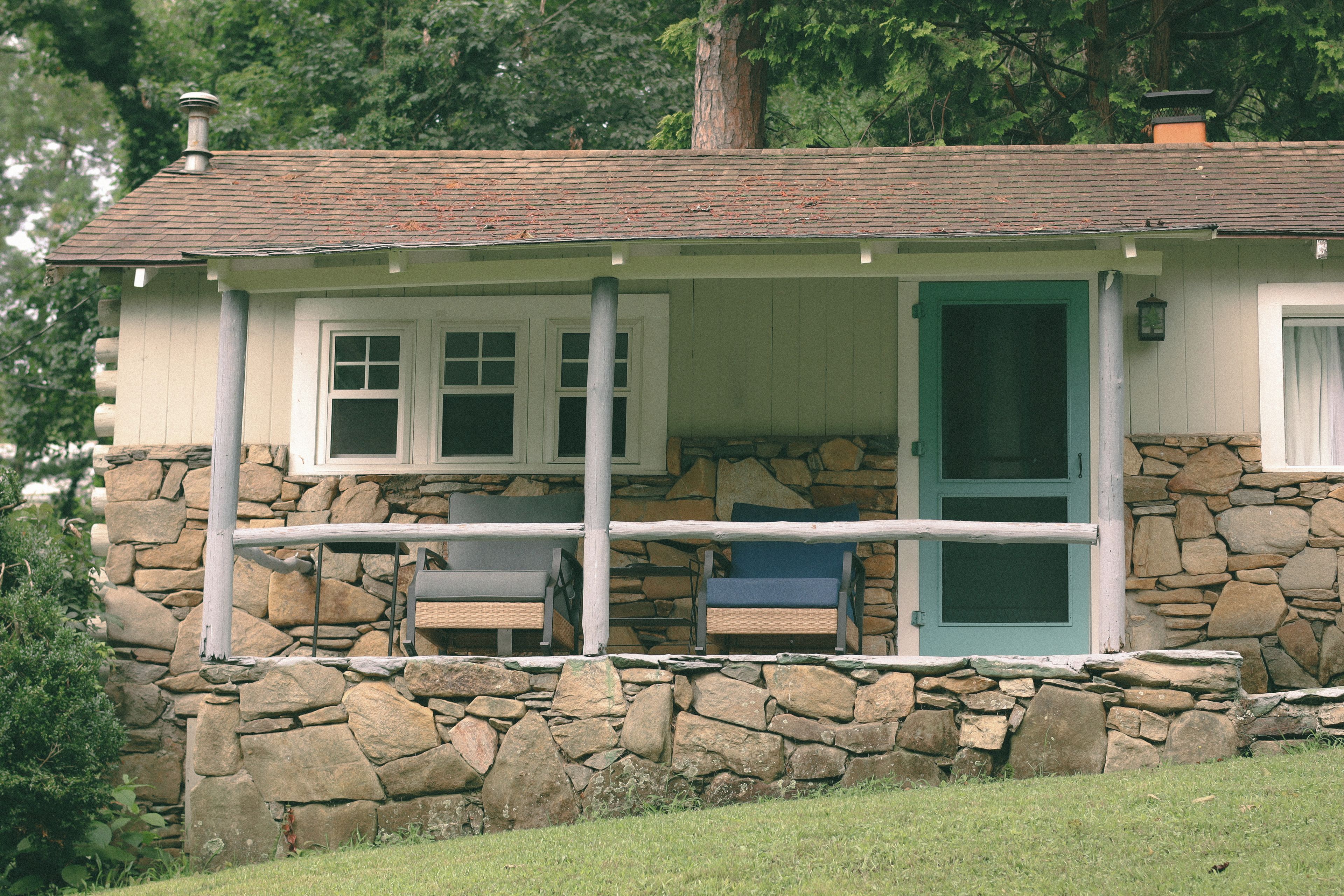 A stone cottage with a porch, a door, and a window.
