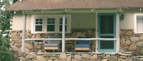 A stone cottage with a porch, a door, and a window.