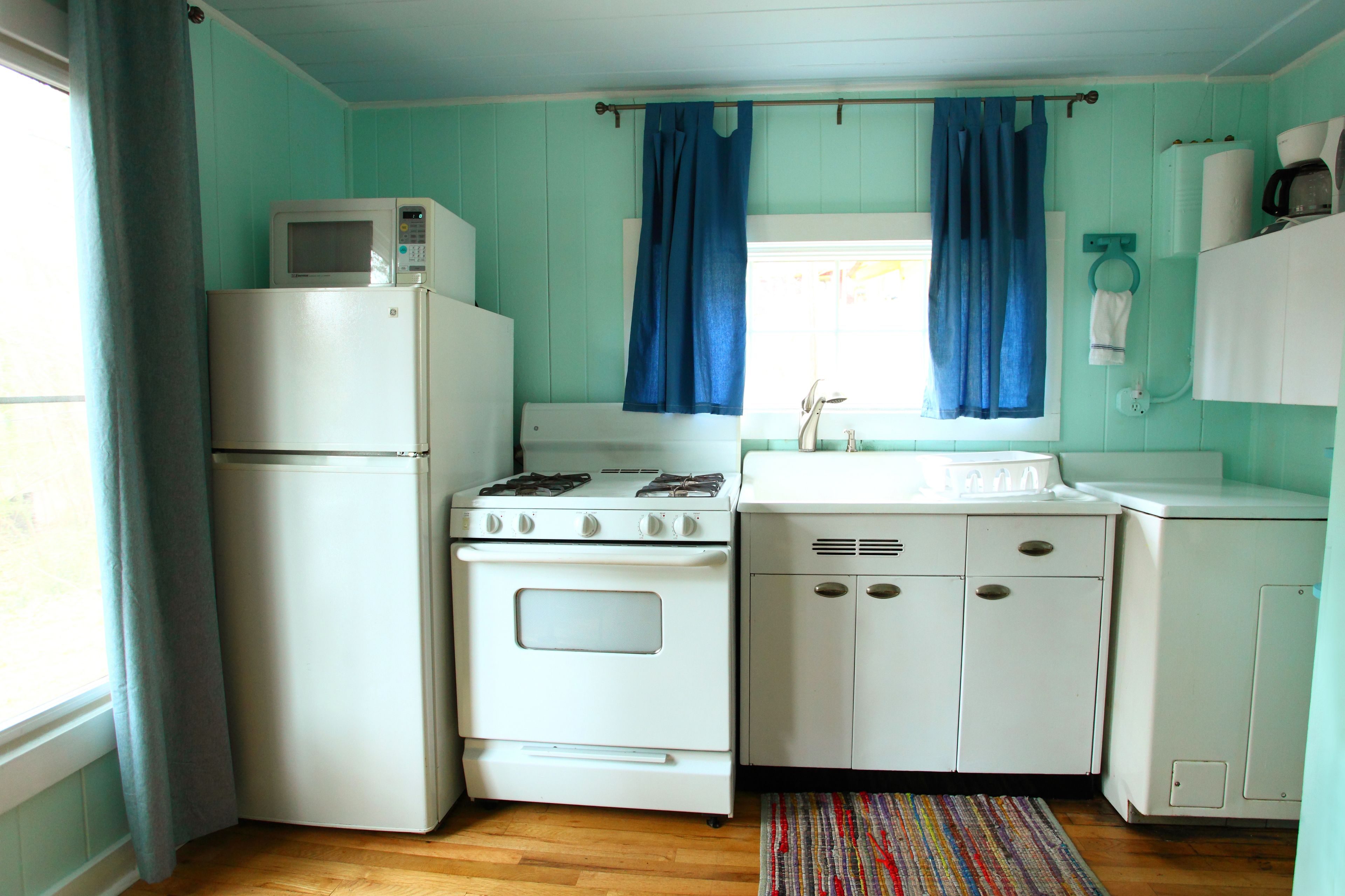 A compact kitchen with a refrigerator, stove, sink, and cabinets.