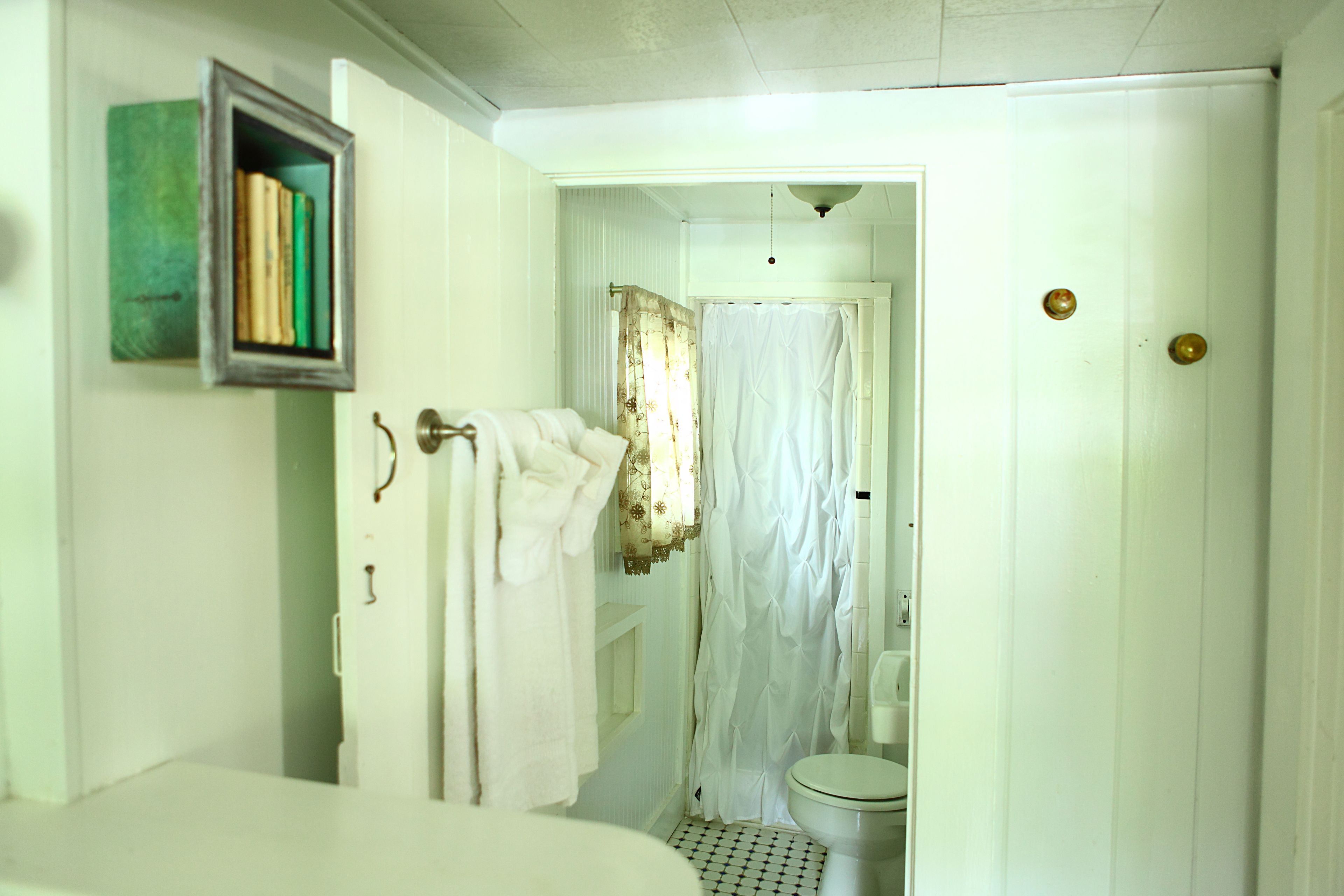 A bathroom with a toilet, a shower curtain, and a towel rack with towels.