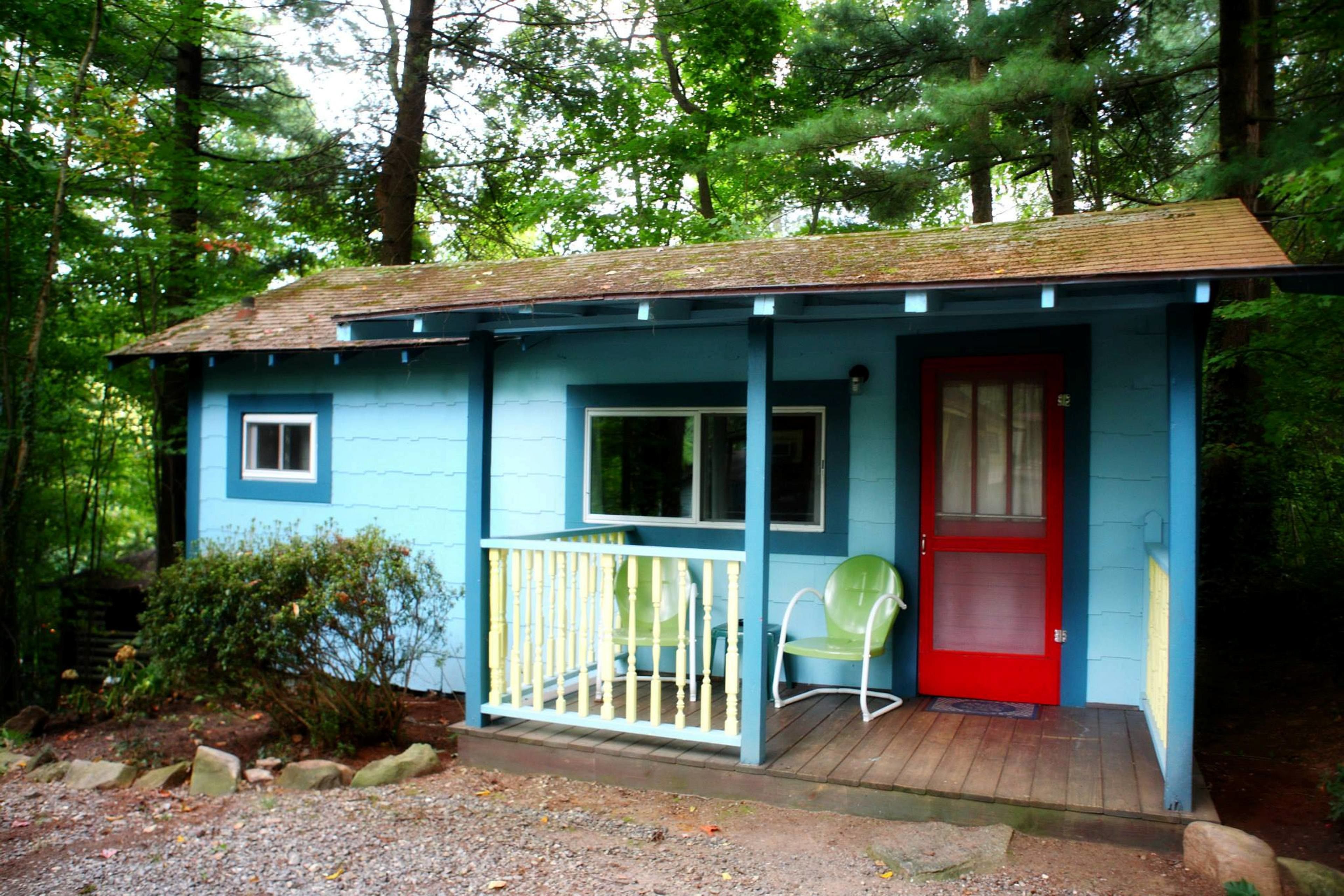A small, single-story cabin with a red door and a porch.