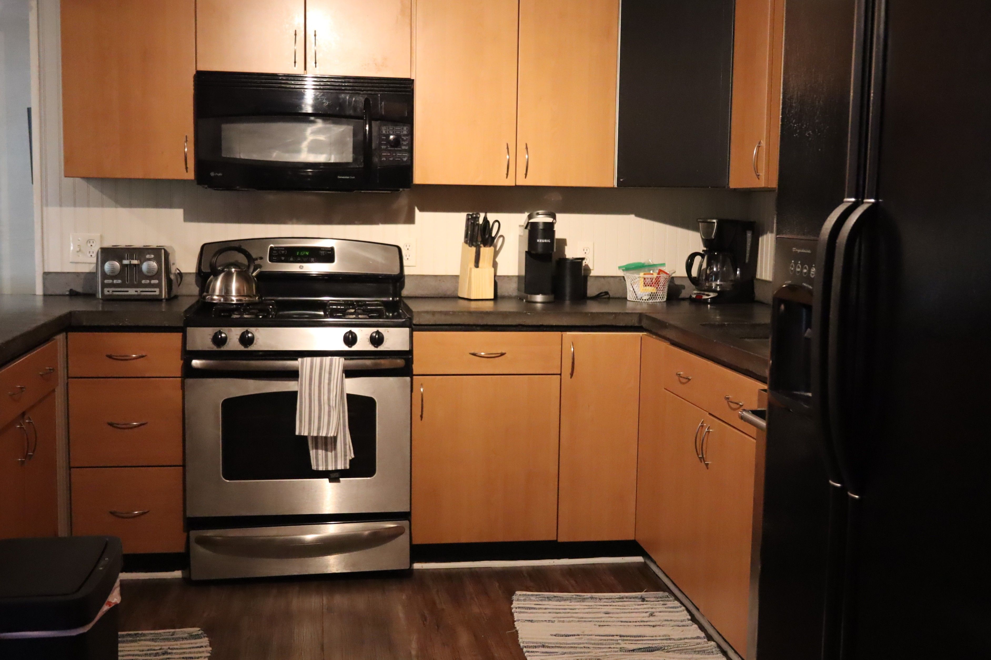 Une cuisine avec des meubles en bois, une cuisinière en acier inoxydable, un four à micro-ondes et un réfrigérateur.