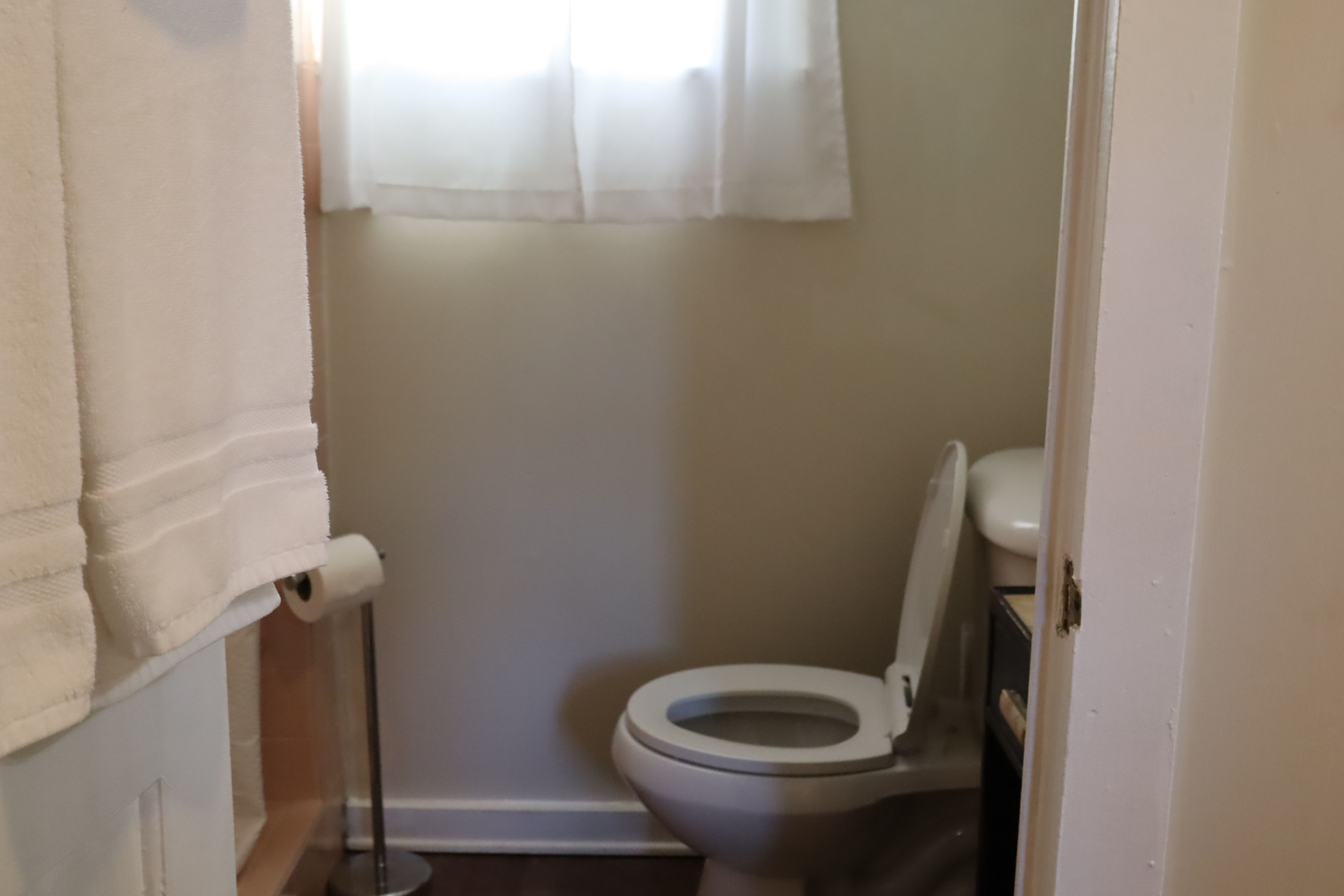 Une petite salle de bain compacte, avec des toilettes, un rouleau de papier toilette et une serviette accrochée au mur.