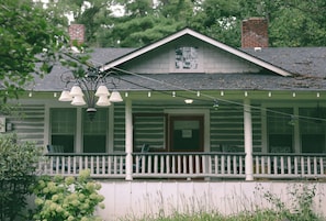 A two-story log cabin with a porch and a covered front porch area.