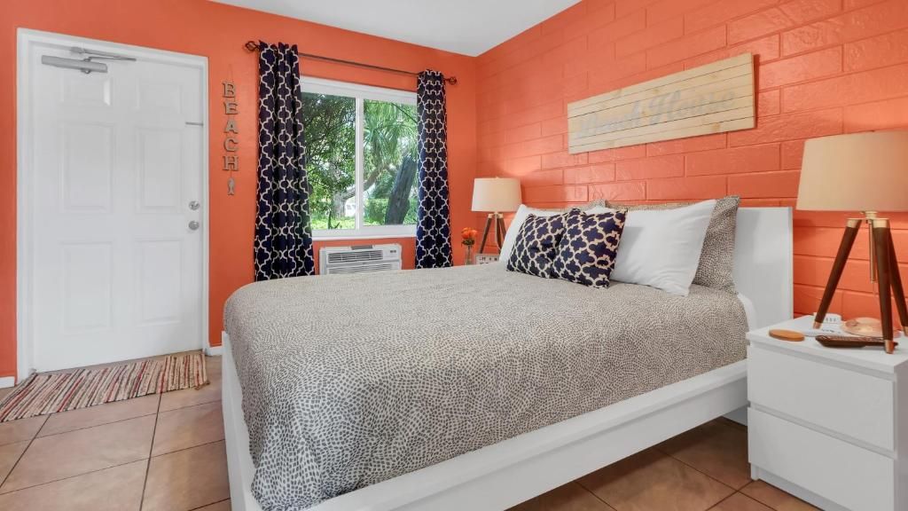 Quarto com cama, duas mesas de cabeceira, janela com cortinas, porta e uma obra de arte pendurada na parede.