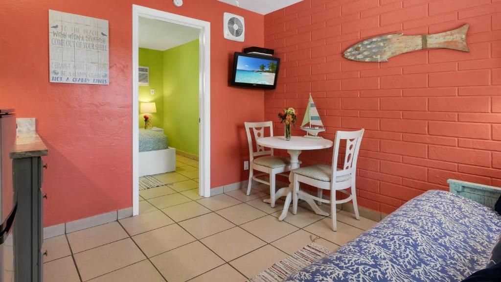 Una habitación con una cama, una mesita con sillas, un televisor y una decoración de peces en la pared.