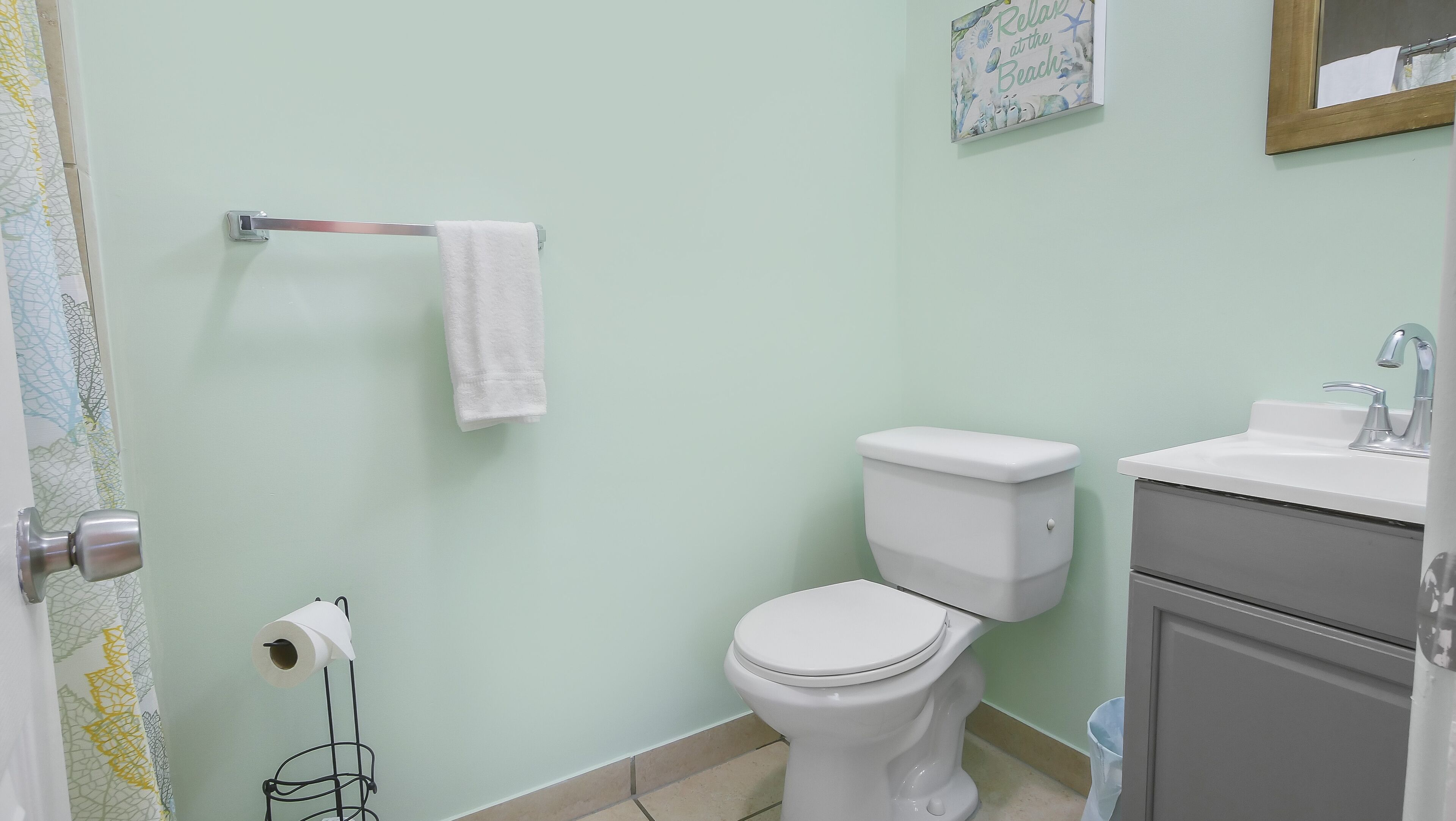 A bathroom with a toilet, sink, and a towel rack.