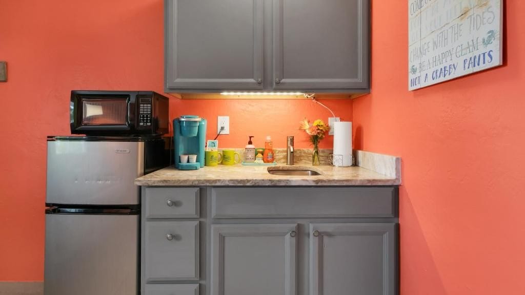 A kitchen with grey cabinets, a microwave, a coffee maker, and a sink.