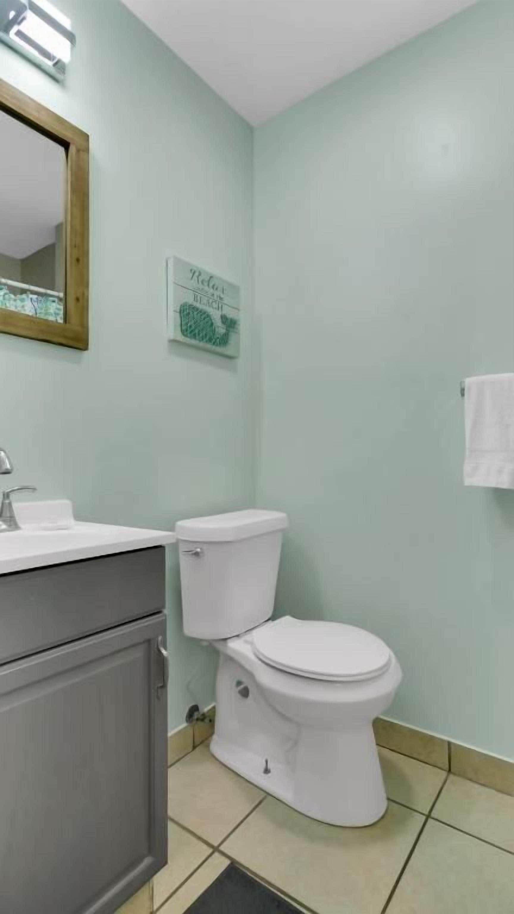 A bathroom with a toilet, sink, and cabinet.