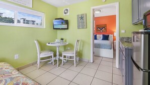 Quarto compacto com área de refeições, cama e cozinha compacta.