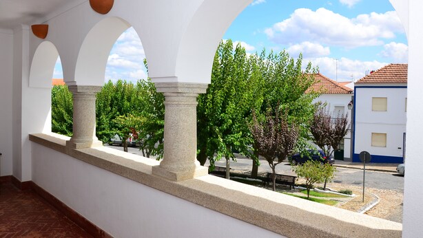 Un espacio al aire libre cubierto con arcos y vistas a árboles y edificios.