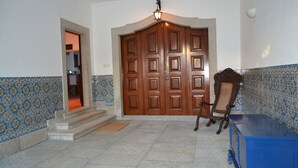 Un pasillo con una puerta doble de madera, una silla y un armario azul.