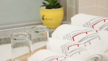 A tray with toiletries including a toothbrush, a towel, and a glass of water, placed on a wooden tray in a bathroom.