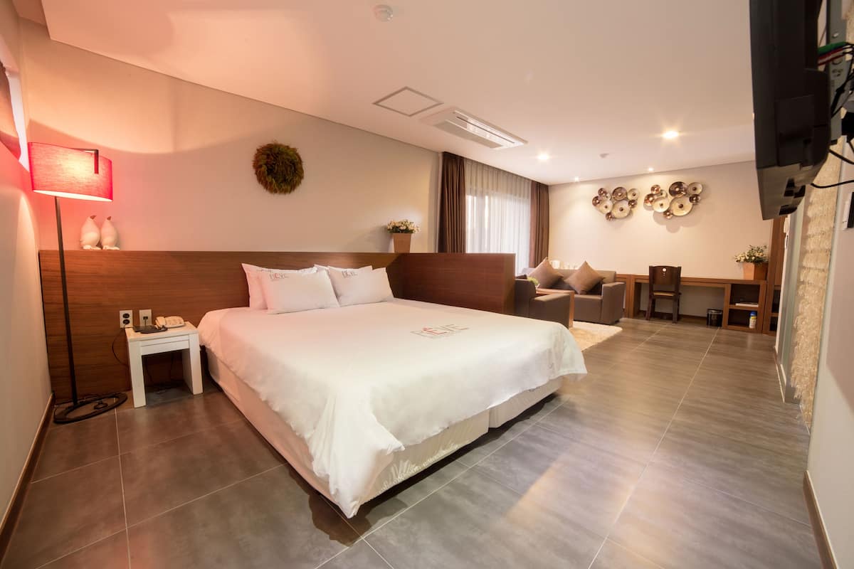 Une chambre d’hôtel moderne avec un grand lit, une table de chevet, une lampe et un bureau avec une chaise.