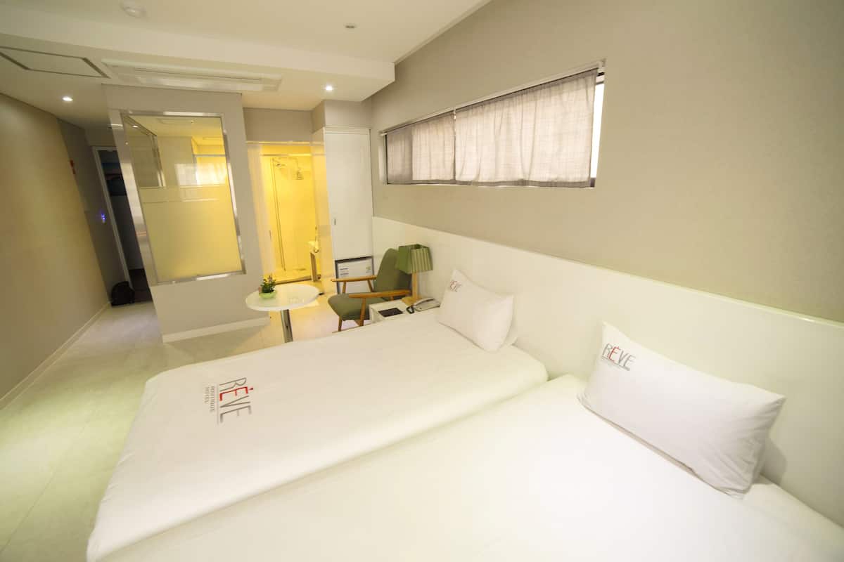 Une chambre d’hôtel avec un lit, un bureau, une chaise et une fenêtre avec des rideaux.