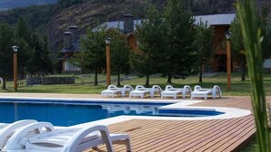 A swimming pool with lounge chairs and a wooden deck.