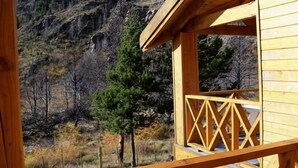 A wooden cabin with a balcony overlooking a mountainous landscape.