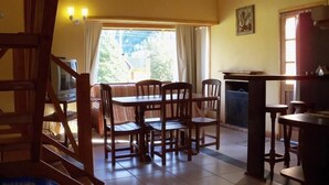 A dining area with a table and chairs, a television, and a view of the outdoors.
