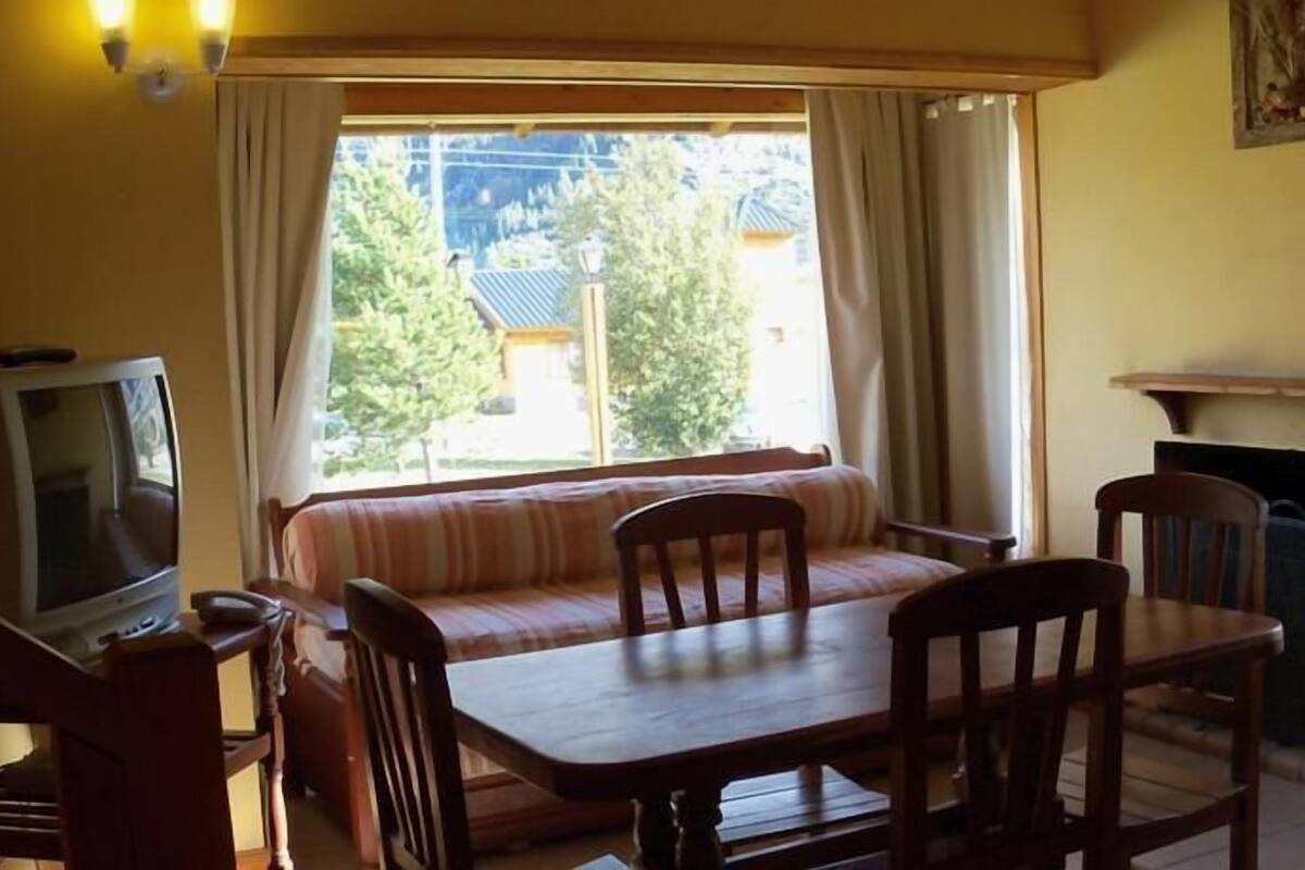 Une pièce chaleureuse avec une table en bois, des chaises, un canapé, un téléviseur et une cheminée.