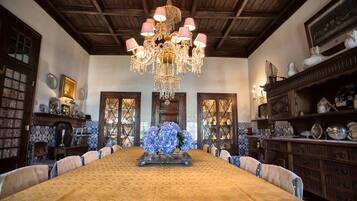 Ein Esszimmer mit einem großen Tisch, Stühlen, einer Chandelier und Holzschränken mit Dekoration.