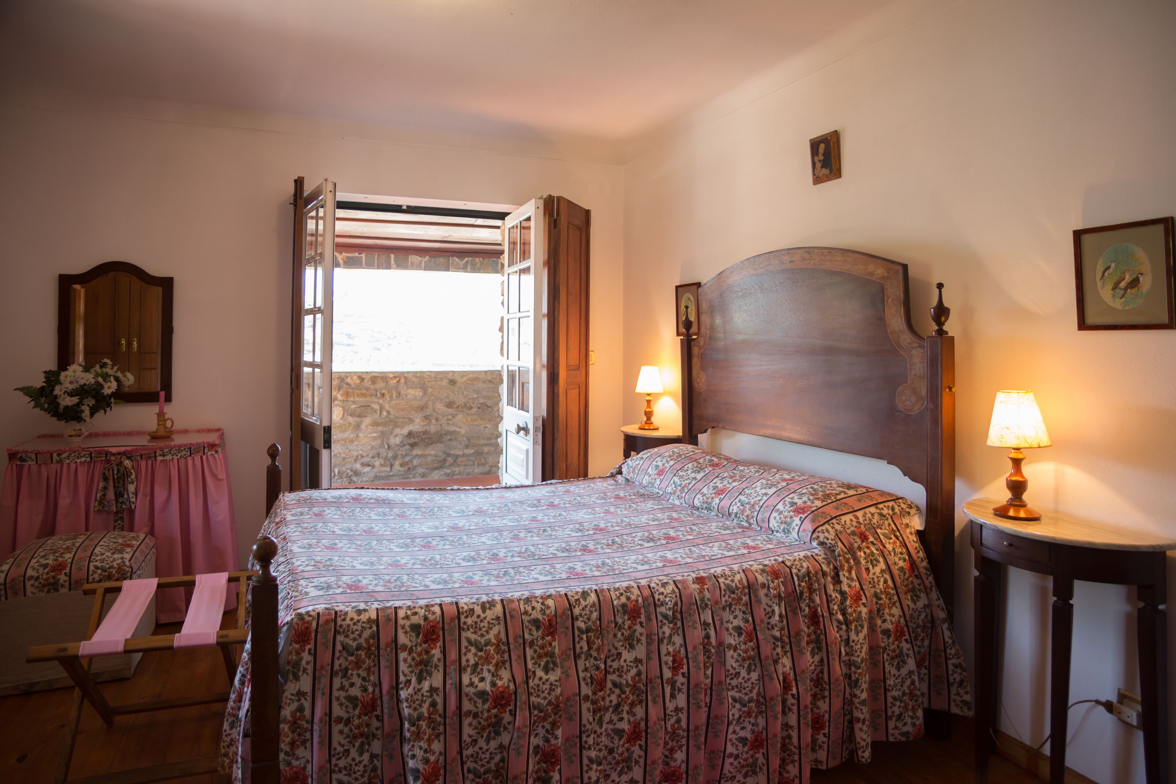 Une chambre à coucher comprenant un lit, deux tables de chevet, une commode, une coiffeuse et une fenêtre avec des rideaux.