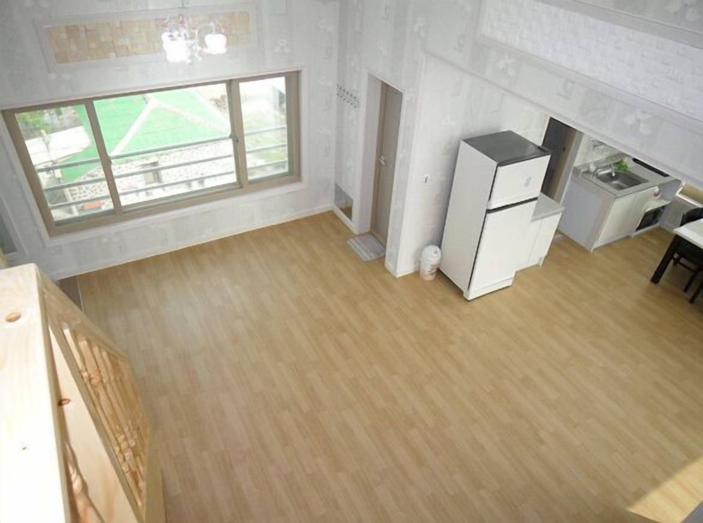A kitchen with a large window, a refrigerator, and a sink.