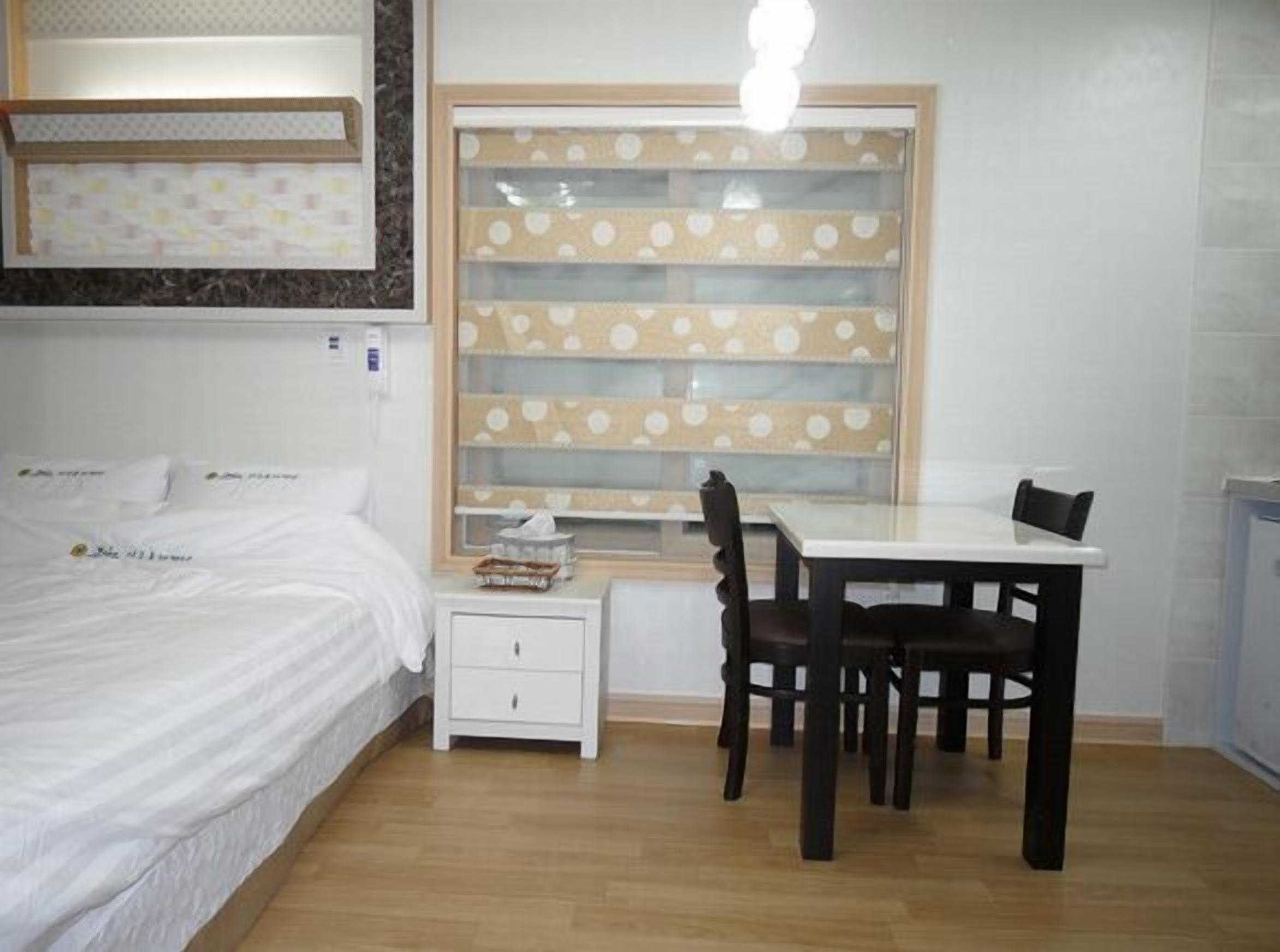 Un dormitorio con cama, mesita de noche y ventana con cortina de lunares.