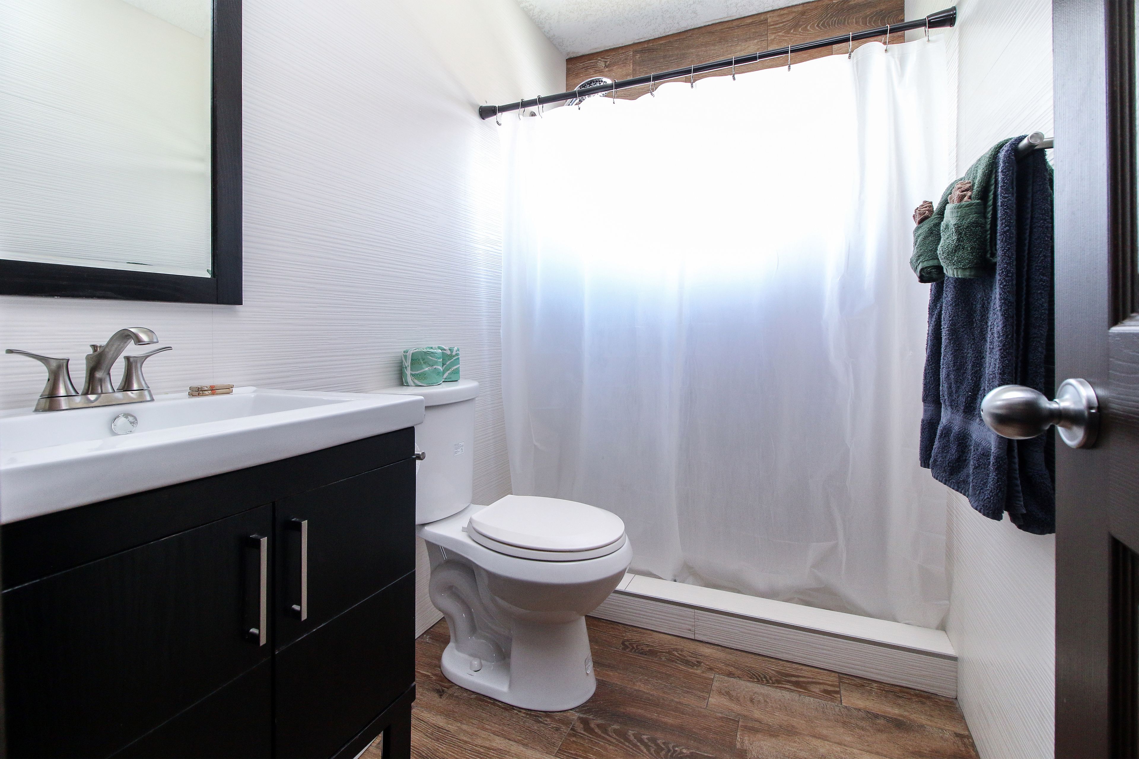 A bathroom with a white toilet, a sink with a mirror, and a shower curtain.