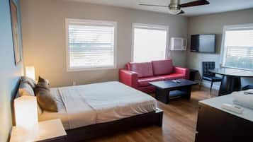 A modern hotel room with a bed, a red sofa, a small table, and a TV.