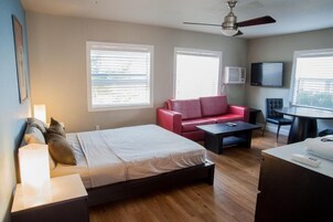 A modern hotel room with a bed, a red sofa, a small table, and a TV.