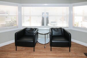 A room with two black leather chairs, a small round table, and large windows with blinds.