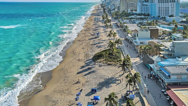 A coastal hotel with a beach view, multiple floors, and a mix of modern and traditional architecture. - Sun Beach Inn (Hollywood)