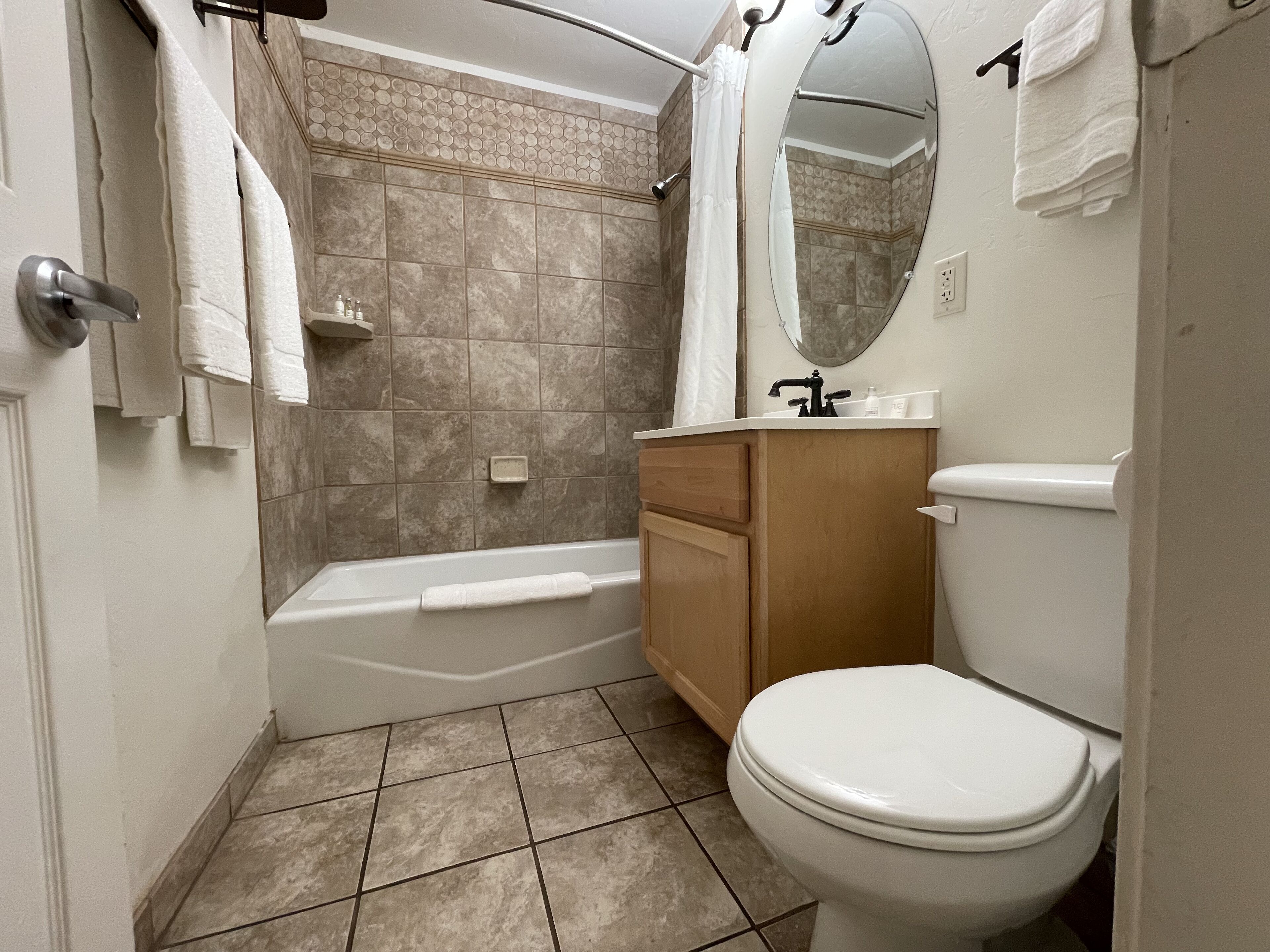 A bathroom with a bathtub, toilet, vanity, and a mirror.